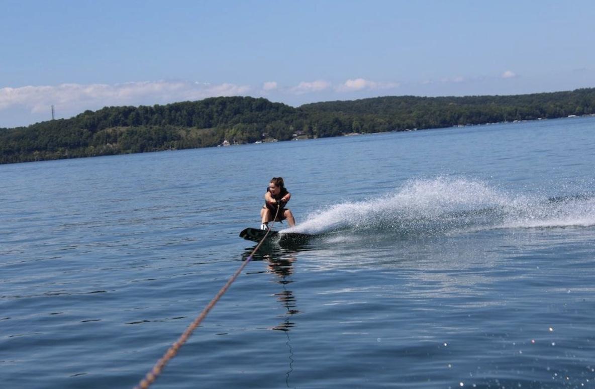 A boy wakeboarding on a lake with mountains in the background.